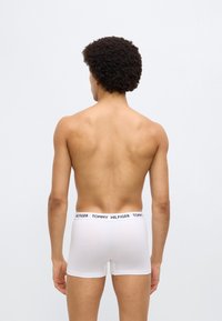 Άσπρο βαμβακερό μπόξερ με μαύρη ελαστική μέση που φέρει το λογότυπο "TOMMY HILFIGER", όψη από πίσω. Λείο ύφασμα και εφαρμοστή σχεδίαση.
