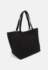 Black canvas tote bag with two sturdy handles, a spacious interior, and a smooth texture. The top edge is open, showcasing the beige lining.