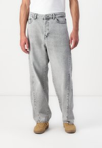 Jeanși din denim gri deschis cu o croială relaxată, design cu cinci buzunare și un aspect ușor decolorat. Au nasture la fermoar și bucle pentru curea.