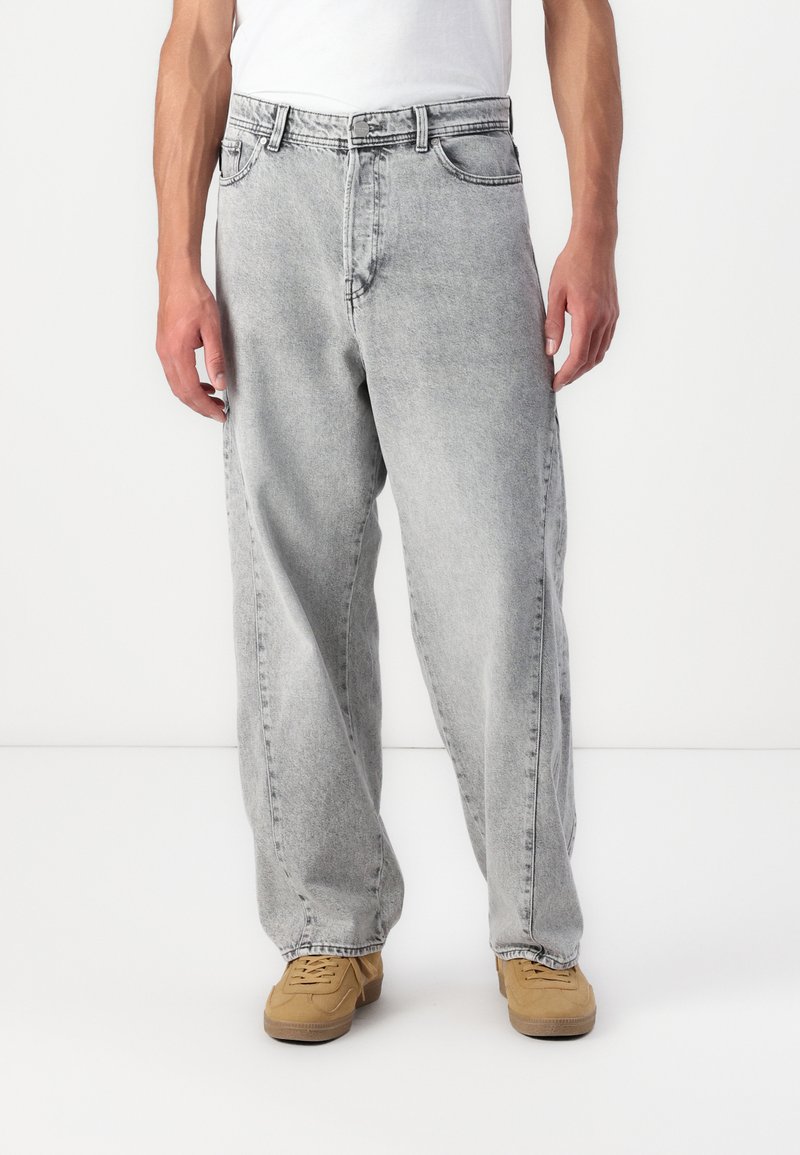 Jeanși din denim gri deschis cu o croială relaxată, design cu cinci buzunare și un aspect ușor decolorat. Au nasture la fermoar și bucle pentru curea.