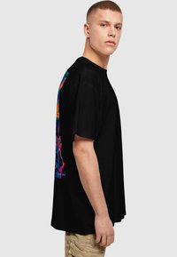 Camiseta de algodón negra con un colorido estampado gráfico en la parte posterior. El diseño incluye formas abstractas en tonos vibrantes.