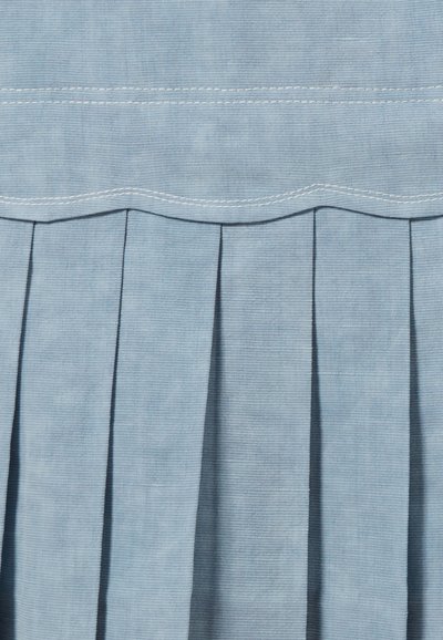 Tissu bleu clair présentant une texture subtile avec des rayures verticales. Le design comprend des plis et un accent brodé ondulé en haut.