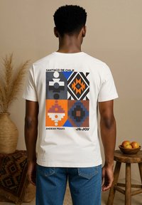 T-shirt en coton blanc présentant un imprime graphique géométrique en orange, bleu, noir et gris avec les textes "Santiago du Chili" et "Pics Andins."