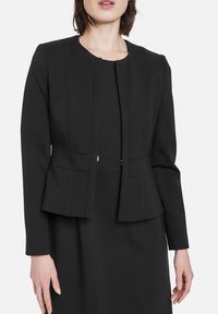 Schwarzer Blazer mit langen Ärmeln, strukturierten Schultern und schmaler Taille. Verfügt über ein gerades Design und minimale Hardware-Details.