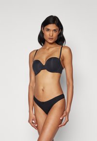 Conjunto de bikini negro que incluye un sujetador moldeado con aros y una braguita de corte bajo. Tela suave con mínimas embellishments y tirantes ajustables.