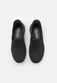 Svarta mesh slip-on skor med rund tå och texturerad yta. Har en mjuk innersula och en gummisula för bra grepp.