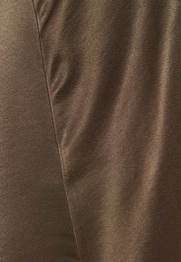 Brun satin tyg med en slät textur, med en subtil glans och lätt rynkor, som visar en mjuk, hängande look.