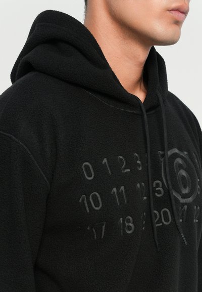 Svart fleece hoodie med en framficka i kangaroo-stil, en huva med dragningar och präglade siffror och mönster på tyget.