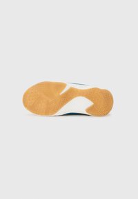 Semelle de chaussure avec un mélange de caoutchouc gomme texturé en orange et blanc, présentant un motif en zigzag pour une traction et une stabilité accrues.