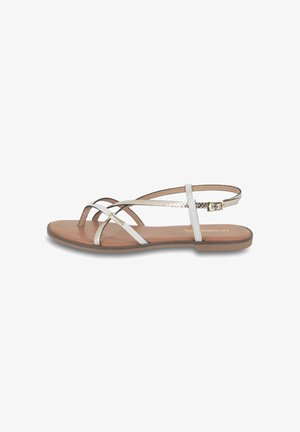 Flat sandals with a light brown sole, white and metallic straps, and a buckle closure. Straps feature a cross design for a minimal look.