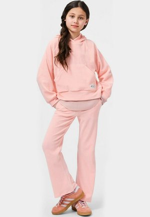 Roze fleece hoodie met een voorzak en geribbelde zoom, gecombineerd met bijpassende flare-broeken. Kenmerkt zich door een zachte textuur en een relaxte pasvorm, gedragen met roze schoeisel.