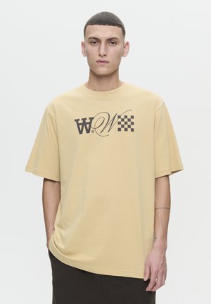 Beige T-Shirt mit kurzen Ärmeln und lockerer Passform, aus weichem Stoff gefertigt, mit einem aufgedruckten Logo im dunkelbraunen Schachbrettmuster.