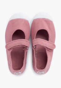 Zapatillas de lona rosa con puntera redonda, cinta de velcro, costados cortados y suelas de goma blanca. Textura suave, diseño casual.