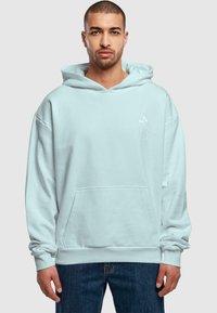 Felpa blu chiaro realizzata in tessuto morbido. Presenta una tasca a marsupio e un design outline floreale bianco sul petto. Vestibilità rilassata, maniche lunghe.