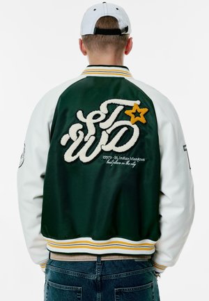 Green and white varsity jacket with embroidered text, a yellow star, and a striped ribbed hem. Textured fabric with logo detail on back.