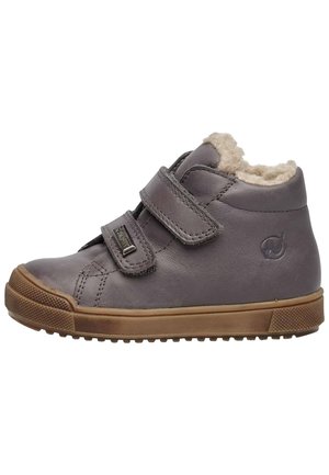 Chaussure montante en cuir gris avec deux bandes Velcro, doublure en molleton beige, semelle en caoutchouc et accents texturés sur les orteils et le talon.
