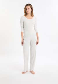 Lichtgrijze geribbelde langslavende top en bijpassende broek, met een ronde halslijn en een recht gesneden ontwerp, voorzien van een gestructureerde stof en onafgewerkte zoomaccenten.