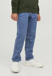 Blå denimjeans med rak skärning, med en ljus tvätt, kontrasterande sömmar och sidofickor, i kombination med vita sportskor.