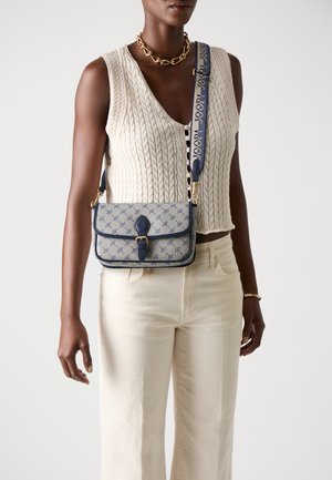 Crossbody tas in een patroonstof, met een marineblauwe rand, knoopsluiting en een afneembare schouderband met logo-details.
