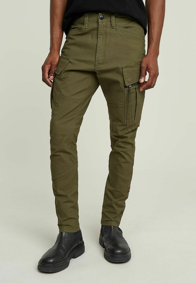 Pantaloni cargo verde oliva con multiple tasche, dettaglio con zip sul lato, vestibilità affusolata, materiale in cotone e cuciture a contrasto.