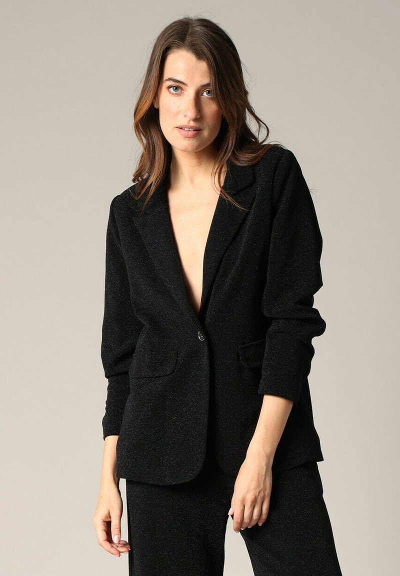 Zwarte blazer gemaakt van een gestructureerde stof met een subtiele glans, voorzien van een enkele knoopsluiting en twee voorzakken, in een getailleerde pasvorm.
