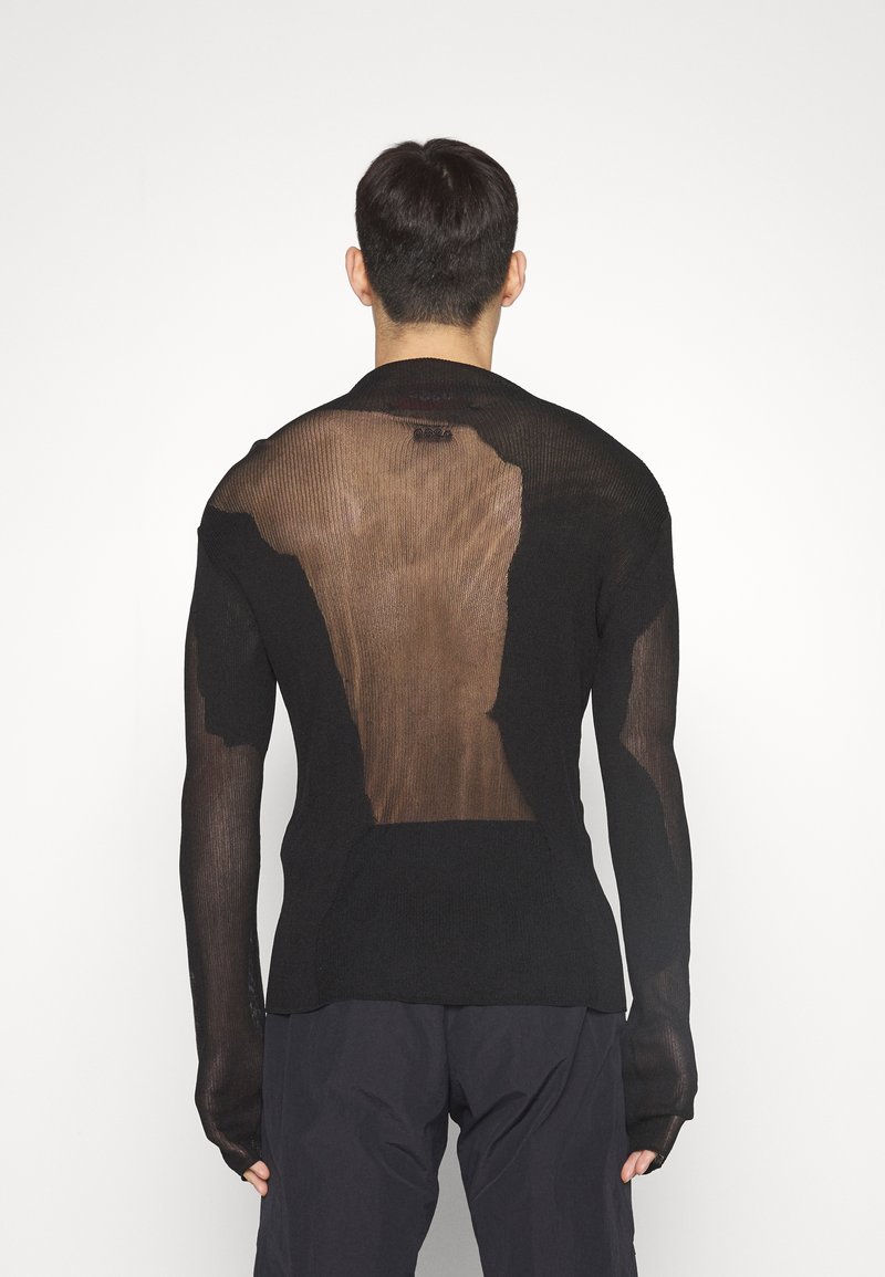 Maglione nero a maglia con maniche lunghe, caratterizzato da un pannello posteriore trasparente e una trama testurizzata. Finitura liscia con silhouette aderente.