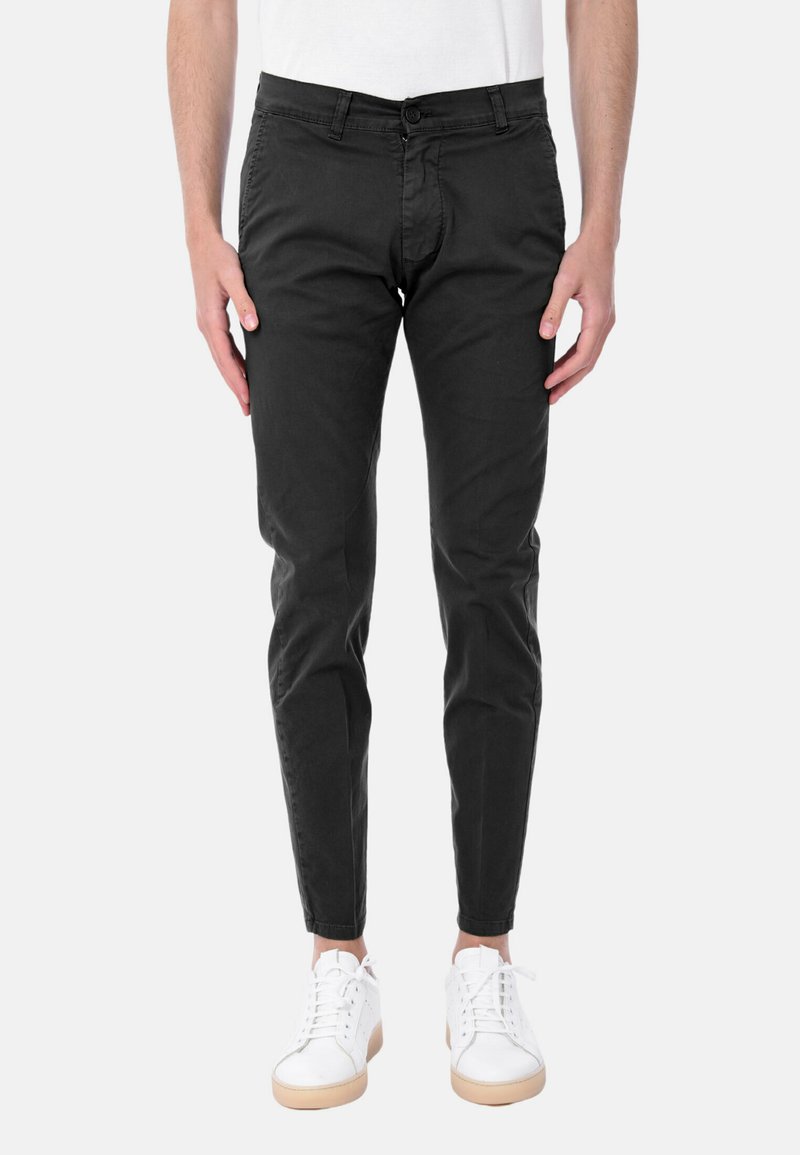 Chino neri con vestibilità dritta, dotati di chiusura con bottone, dettagli sulle tasche e una texture del tessuto liscia, abbinati a sneaker bianche.