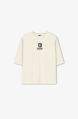 T-shirt oversize di colore crema realizzata in cotone, con un design grafico nero sul davanti, che include testo e un'immagine astratta.
