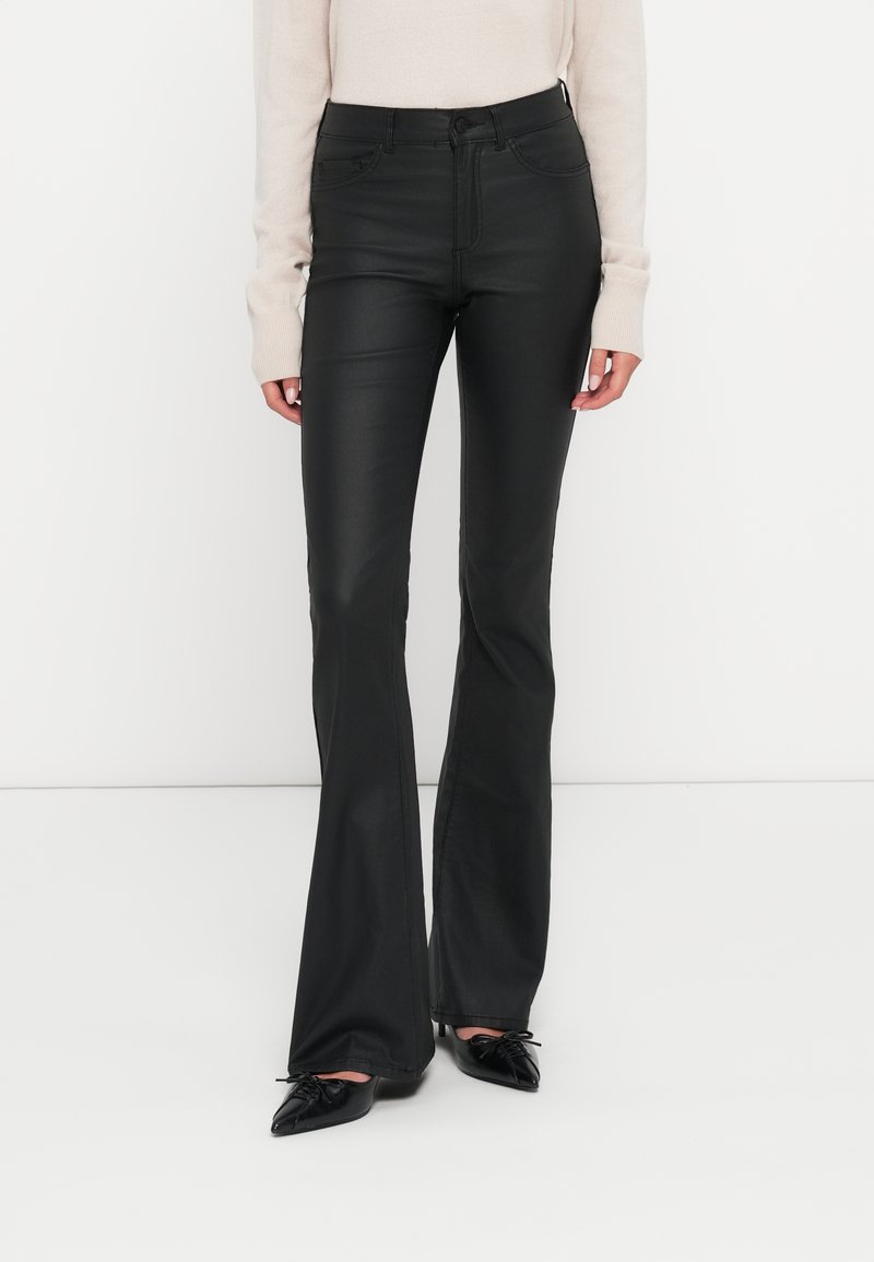 Crne široke traperice glatke teksture, visokog struka, s kontrastnim šavovima i prednjim džepovima. Uparen s svijetlosmešavom majicom.