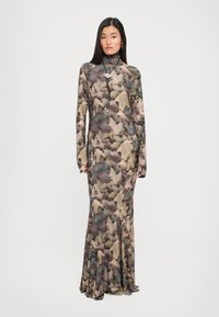 Rochie cu mâneci lungi, realizată dintr-un material ușor, cu un model de frunze în tonuri stinse de verde și maro, având un guler înalt și o fustă evazată.