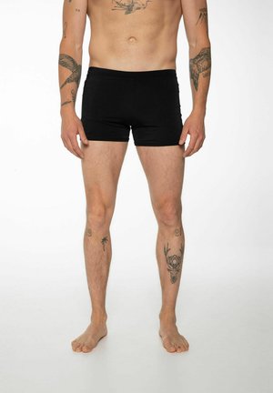 Schwarze Badeshorts aus dehnbarem Material, mit einem enganliegenden Design, glatter Textur und ohne sichtbare Muster oder Hardware-Details.