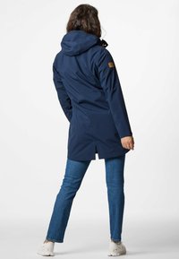 Parka impermeabile blu navy con cappuccio, dotata di chiusura con zip, tasche laterali e orlo spaccato. Il materiale è liscio e resistente.
