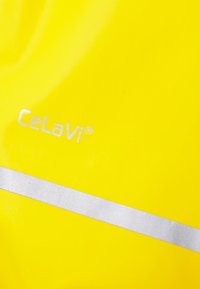 Rumena vodoodporna tkanina z gladko teksturo ima srebrno odsevno pásko in natisnjen bel "Celavi" logotip.