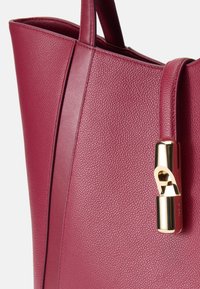 Sac en cuir bourgogne profond avec une finition texturée, présentant un accent en métal doré sur le côté et deux anses robustes.