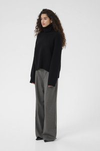 Crop turtleneck sweater in black knit, paired with high-waisted, wide-leg gray trousers with a textured finish, and black shoes.