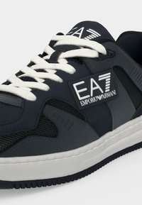 Μαύρο και γκρι sneaker EA7 Emporio Armani με λευκά κορδόνια και λευκή σόλα, με εμφανές λογότυπο της μάρκας στο πλάι και στη γλώσσα.