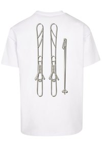 White T-shirt featuring silver metallic graphic of three safety pins. The design includes various shapes and intricate detailing on the pins.
