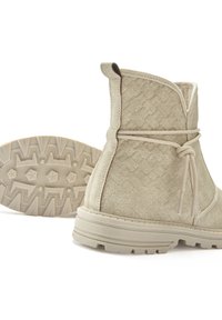 Beige Knöchelstiefel aus strukturiertem Wildleder, mit Schnürdesign und robuster Gummisohle mit einem Sternmuster-Profil.
