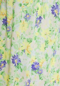 Kukkakuvioinen kangas, jossa on keltaisia, violetteja ja vihreitä kukkia vaalealla taustalla. Rakenteellinen kuvio, jossa on vaihtelevaa kukkien kokoa ja muotoa.