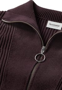 Burgunderfarbener Strick-Zip-Hoodie mit geripptem Muster, ausgestattet mit einem silbernen Reißverschluss und einem runden Zipper. Etikett trägt die Aufschrift „hessnatur.“