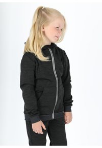 Felpa nera con zip e un motivo testurizzato, dotata di cappuccio e tasche, abbinata a pantaloni coordinati, indossata da un bambino con capelli lunghi.