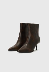 Bottines marron à bout pointu avec une finition en cuir lisse, dotées d'une fermeture éclair sur le côté et d'un talon haut élancé.