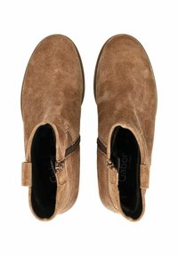 Une paire de bottes de cheville en daim marron avec des fermetures éclair sur les côtés, vues du dessus sur un fond blanc.