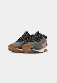 Black and gray athletic shoes with a textured upper, orange accents, and a gum sole. Features a padded collar and reflective detailing.