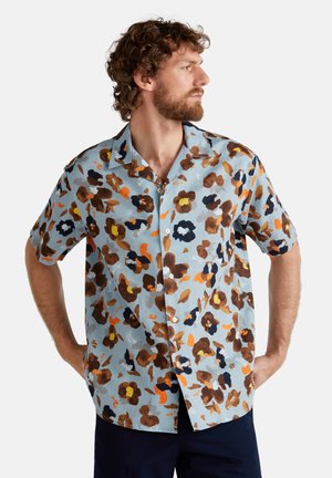 Korte mouwen overhemd van lichtblauwe stof met een bloemenpatroon in bruin, oranje en marineblauw. Voorzijde met knopen en een ontspannen kraag.