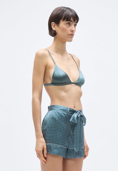 Bralette triangolare in satin verde acqua con spalline sottili abbinato a pantaloncini verde acqua con fantasia, caratterizzati da un fiocco e dettagli a contrasto.