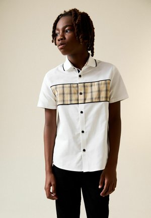 Kurzarmhemd aus weißer Baumwolle mit schwarzem Piping, versehen mit einer gelben Karofrontblende und schwarzen Knöpfen. Entworfen für eine entspannte Passform.