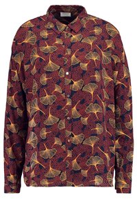 Chemise à manches longues bleue marine avec un motif floral rouge agrémenté de feuilles jaunes. Boutonnage sur le devant, col et coupe décontractée.