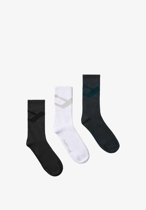 Trzy skarpety do połowy łydki w kolorach czarnym, białym i ciemnoszarym, każda z kontrastującym wzorem znaku wyboru blisko góry oraz nazwą marki na stopie.