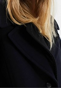 Námořnický vlněný kabát s velkým, skládacím límcem a texturovanou látkou. Obsahuje zapínání na jeden knoflík a měkký, uvolněný střih.